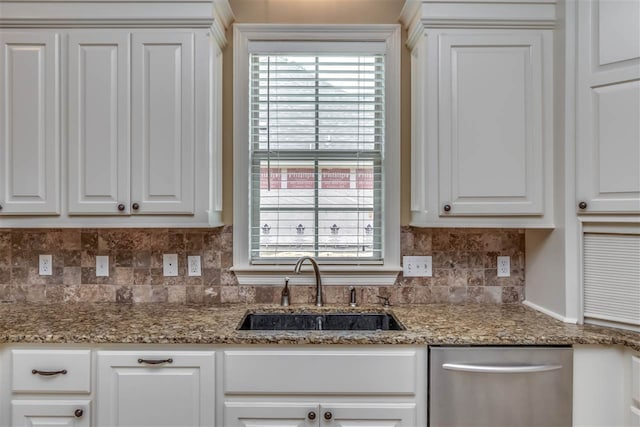 kitchen featuring light stone counters, tasteful backsplash, stainless steel dishwasher, white cabinets, and a sink