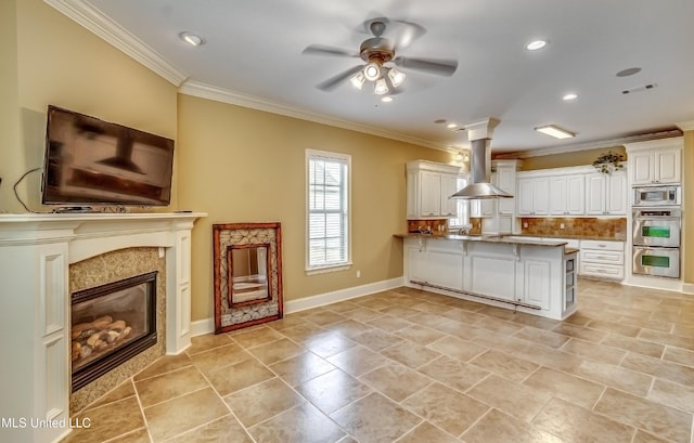 kitchen with a peninsula, island exhaust hood, stainless steel appliances, a fireplace, and backsplash