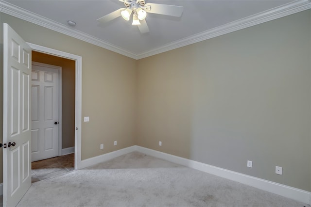 carpeted spare room featuring ornamental molding, ceiling fan, and baseboards