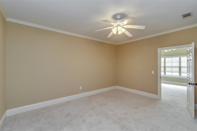 unfurnished room featuring ceiling fan, light colored carpet, visible vents, baseboards, and crown molding