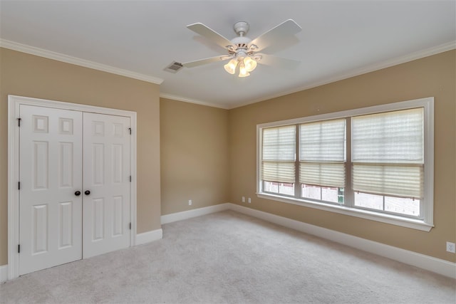 unfurnished bedroom featuring light colored carpet, visible vents, baseboards, a closet, and crown molding