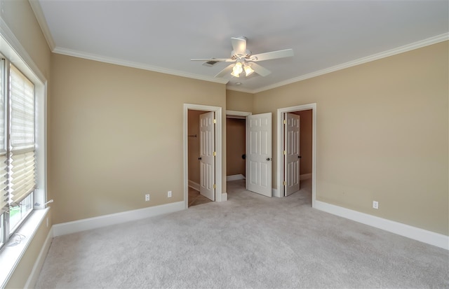 unfurnished bedroom with ornamental molding, carpet, a walk in closet, and baseboards