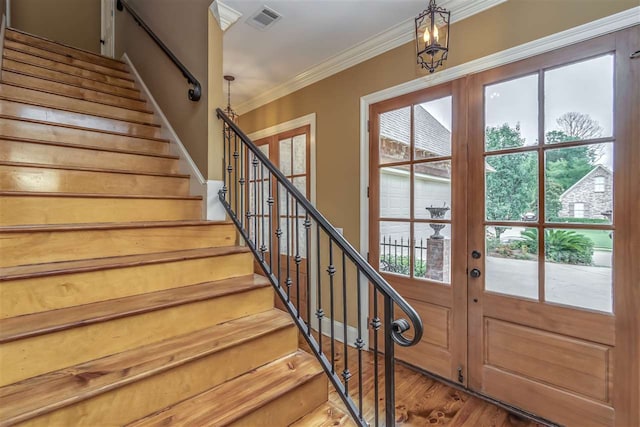 doorway to outside featuring wood finished floors, visible vents, french doors, ornamental molding, and stairway