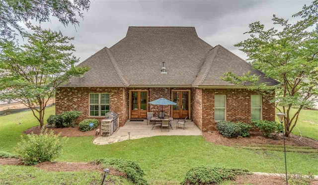 back of house featuring brick siding, a yard, and french doors