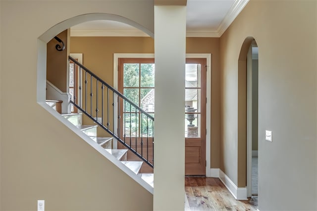 entrance foyer with ornamental molding, stairway, wood finished floors, and baseboards