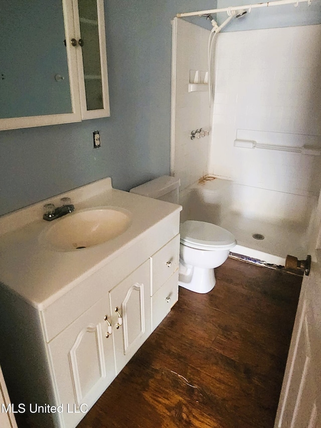 bathroom with a shower, vanity, wood-type flooring, and toilet