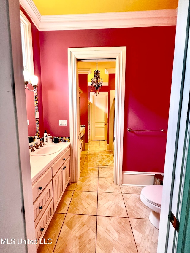 bathroom with crown molding, vanity, a chandelier, and toilet