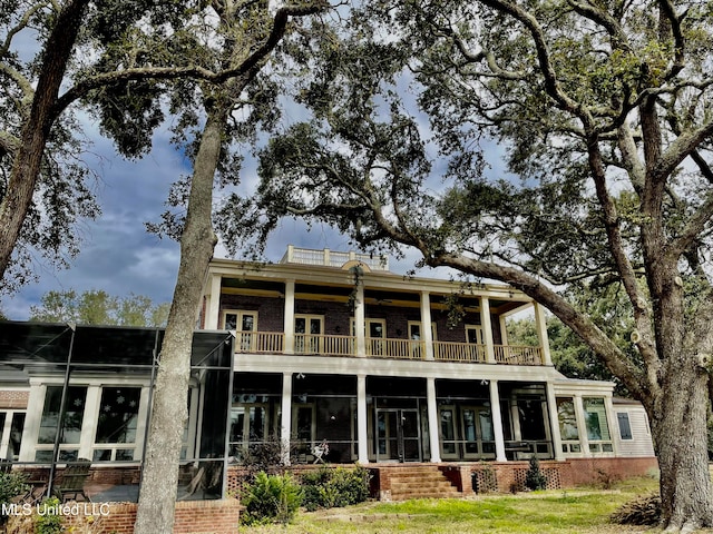 rear view of property with ceiling fan, a balcony, and a sunroom