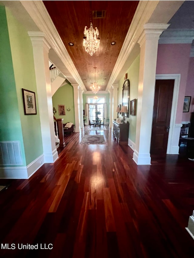 corridor with hardwood / wood-style flooring, a notable chandelier, ornamental molding, wooden ceiling, and ornate columns