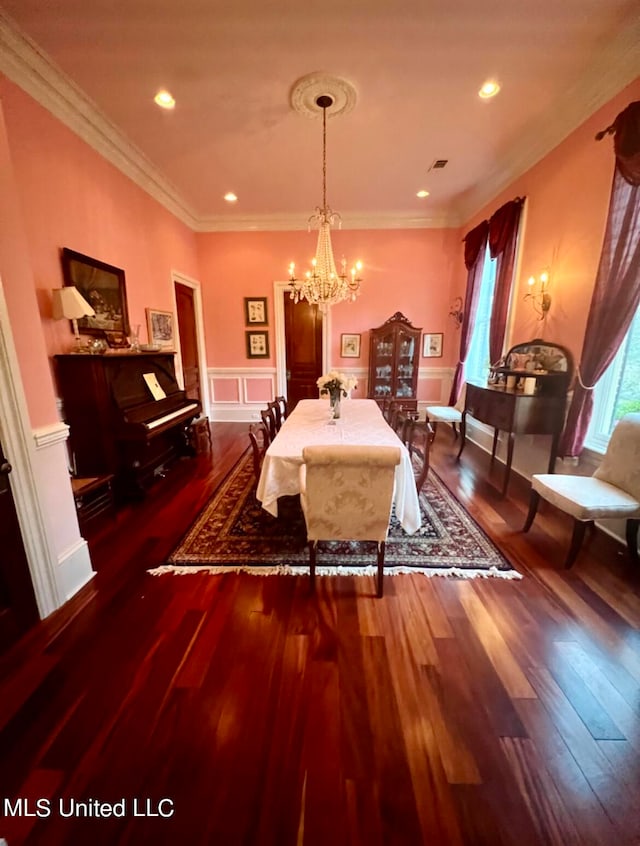 dining area with a notable chandelier, crown molding, and dark wood-type flooring