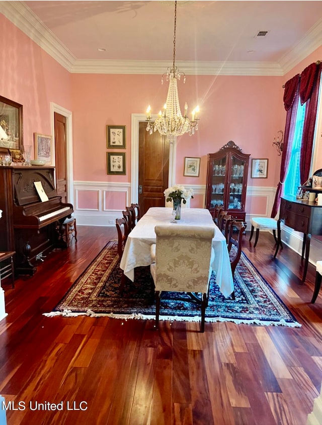 dining area with dark wood-type flooring, crown molding, and a notable chandelier