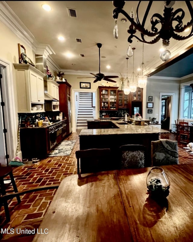 kitchen featuring decorative light fixtures, a kitchen bar, decorative backsplash, ornamental molding, and a spacious island