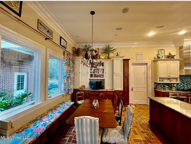 dining space with ornamental molding and a notable chandelier