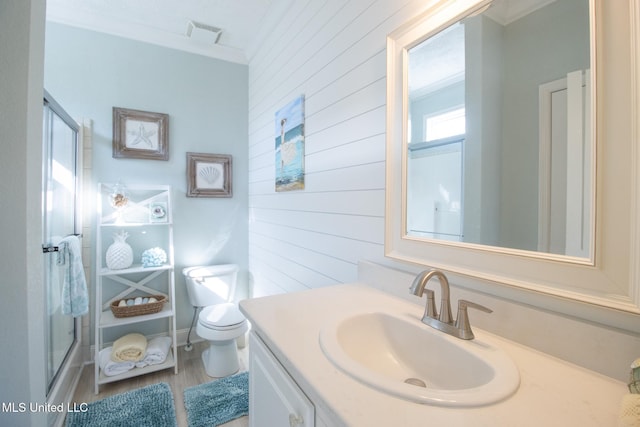 full bathroom with toilet, vanity, ornamental molding, and a shower with shower door