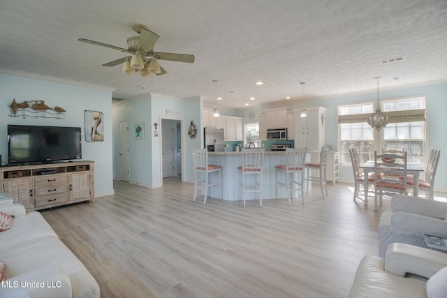 living area with a ceiling fan, visible vents, light wood finished floors, and a textured ceiling