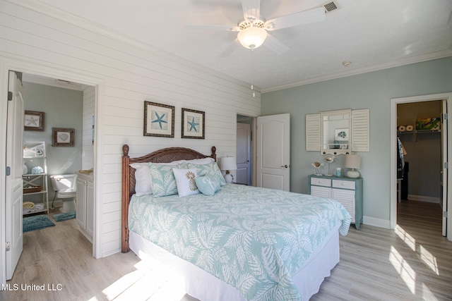 bedroom featuring a walk in closet, visible vents, light wood-style floors, crown molding, and baseboards