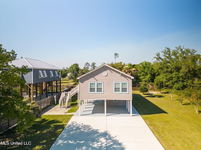 coastal home with a front lawn, fence, concrete driveway, stairs, and a carport