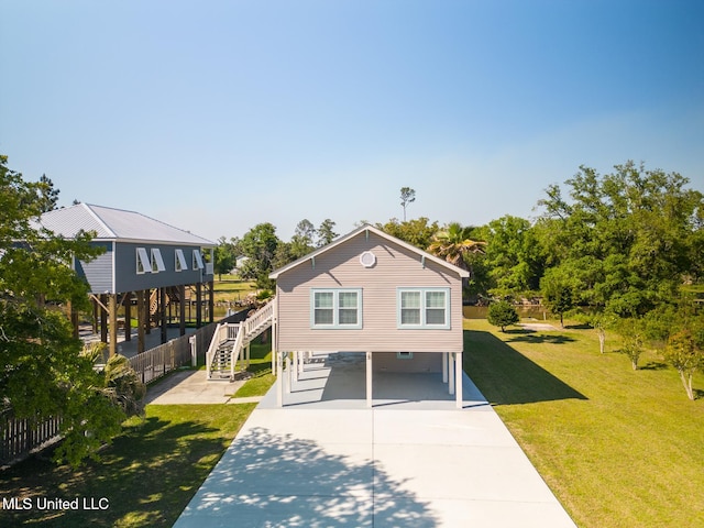 coastal home featuring a carport, driveway, stairs, and a front yard