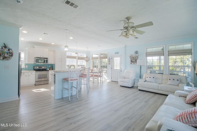 living room with visible vents, ceiling fan, recessed lighting, light wood-style floors, and a textured ceiling