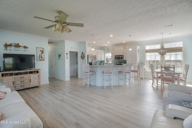 living area with visible vents, a textured ceiling, light wood-style floors, and a ceiling fan