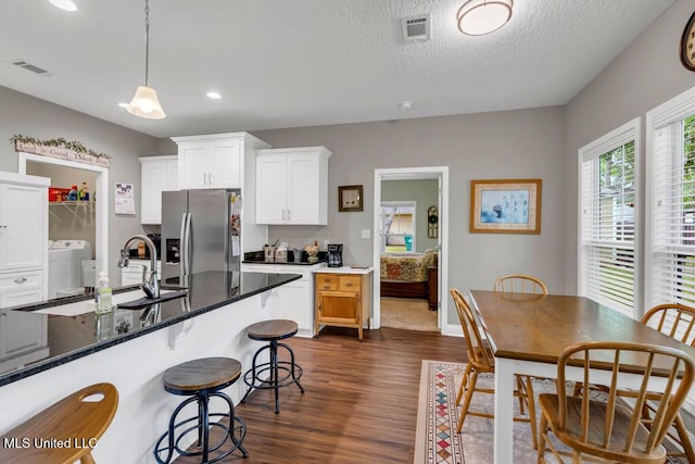 10714 Lilinoe Way, Diamondhead, MS 39525 - kitchen with washer / dryer, stainless steel fridge, visible vents, and dark wood-style flooring