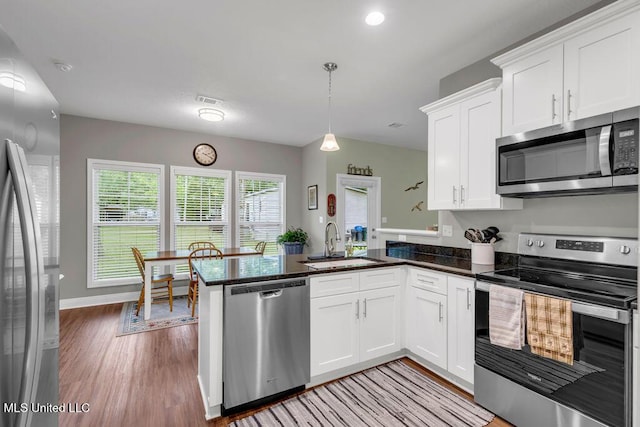 10714 Lilinoe Way, Diamondhead, MS 39525 - kitchen with stainless steel appliances, a peninsula, a sink, light wood-style floors, and white cabinetry