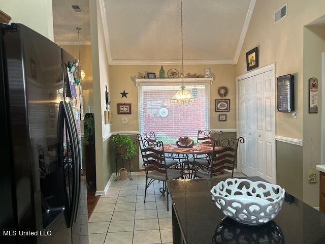 dining room featuring crown molding, vaulted ceiling, and light tile patterned floors