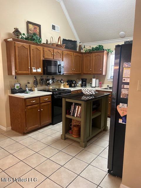 kitchen with light tile patterned floors, a textured ceiling, high vaulted ceiling, black appliances, and crown molding