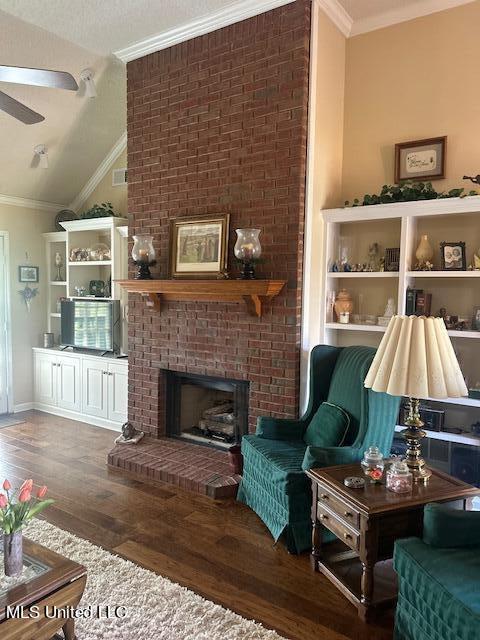 sitting room with dark hardwood / wood-style flooring, a brick fireplace, ceiling fan, vaulted ceiling, and ornamental molding