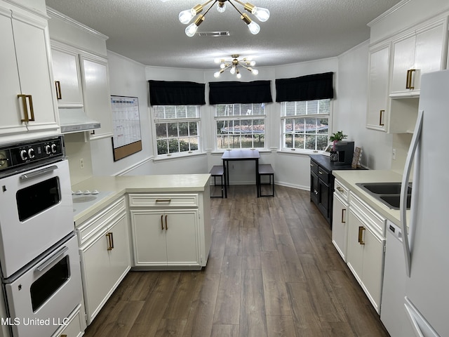 507 Reed Dr, Cleveland, MS 38732 - kitchen featuring a chandelier, a peninsula, light countertops, white appliances, and dark wood finished floors