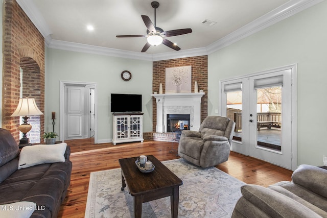 living room featuring french doors, a fireplace, hardwood / wood-style floors, and crown molding