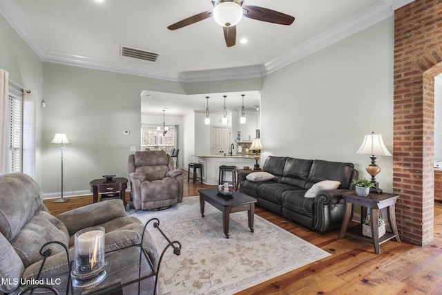 living area with visible vents, crown molding, and wood finished floors