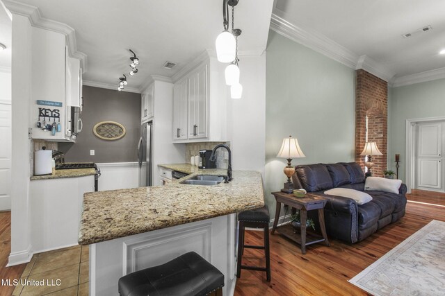 kitchen with visible vents, ornamental molding, stainless steel appliances, a sink, and white cabinetry