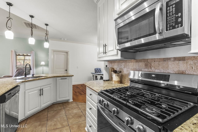 kitchen featuring visible vents, a sink, decorative backsplash, stainless steel appliances, and crown molding