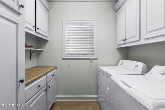 laundry area featuring washer and clothes dryer, cabinet space, and baseboards