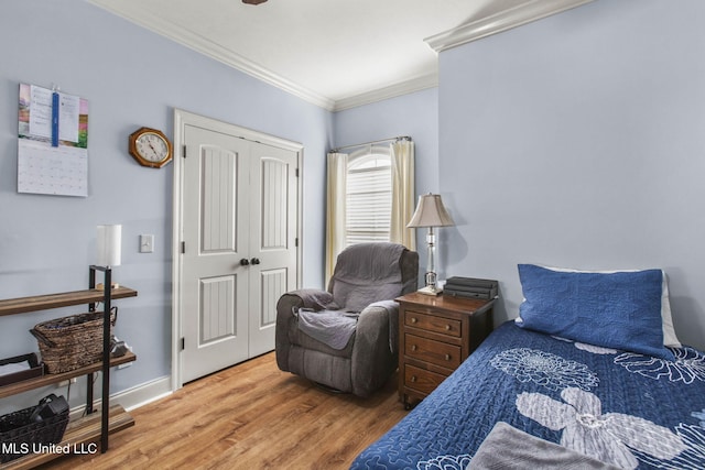 bedroom with a closet, baseboards, wood finished floors, and crown molding