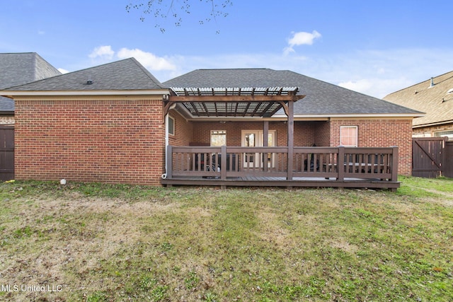 rear view of property with brick siding, a lawn, and fence