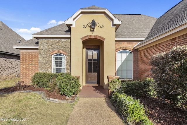 doorway to property with brick siding, stone siding, stucco siding, and a shingled roof