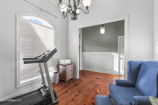 sitting room featuring a chandelier, crown molding, baseboards, and hardwood / wood-style flooring