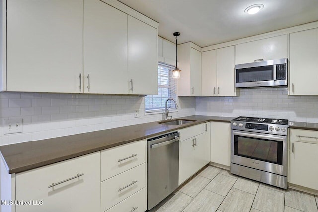 kitchen with sink, pendant lighting, decorative backsplash, and appliances with stainless steel finishes