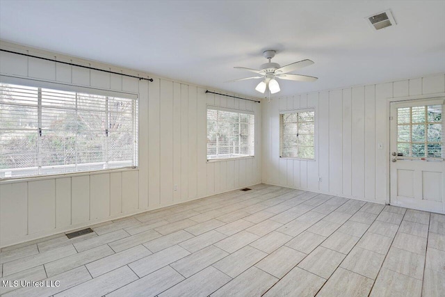 unfurnished room featuring ceiling fan and wood walls