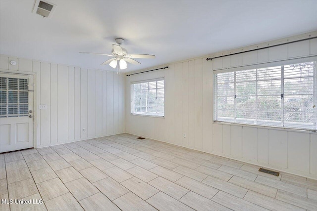 unfurnished room featuring wood walls and ceiling fan