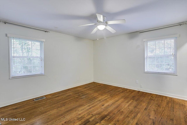 spare room with ceiling fan, plenty of natural light, and dark wood-type flooring