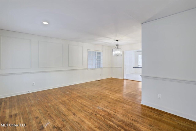 unfurnished living room with a notable chandelier and wood-type flooring