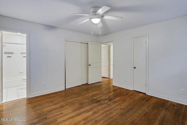 unfurnished bedroom with ceiling fan, dark wood-type flooring, and ensuite bathroom