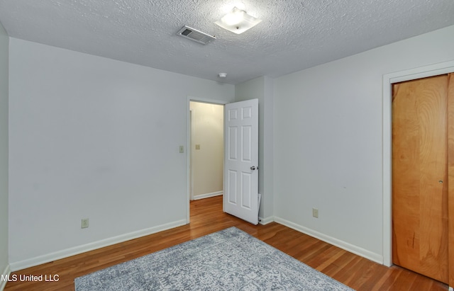315 Church St, Madison, MS 39110 - unfurnished bedroom with wood finished floors, baseboards, and a textured ceiling