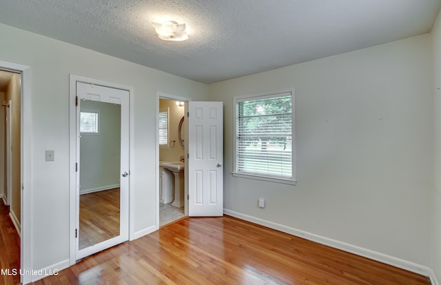 315 Church St, Madison, MS 39110 - unfurnished bedroom with light wood-style floors, baseboards, a textured ceiling, and ensuite bath