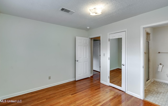 315 Church St, Madison, MS 39110 - unfurnished bedroom featuring light wood-type flooring, baseboards, a textured ceiling, and ensuite bath