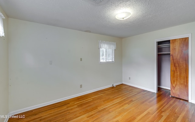 315 Church St, Madison, MS 39110 - unfurnished bedroom featuring light wood-style floors, a textured ceiling, baseboards, and a closet