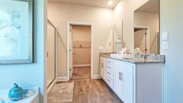 15109 Windmill Ridge Parkway, Diberville, MS 39540 - bathroom featuring wood finished floors, double vanity, a stall shower, a walk in closet, and a tub to relax in